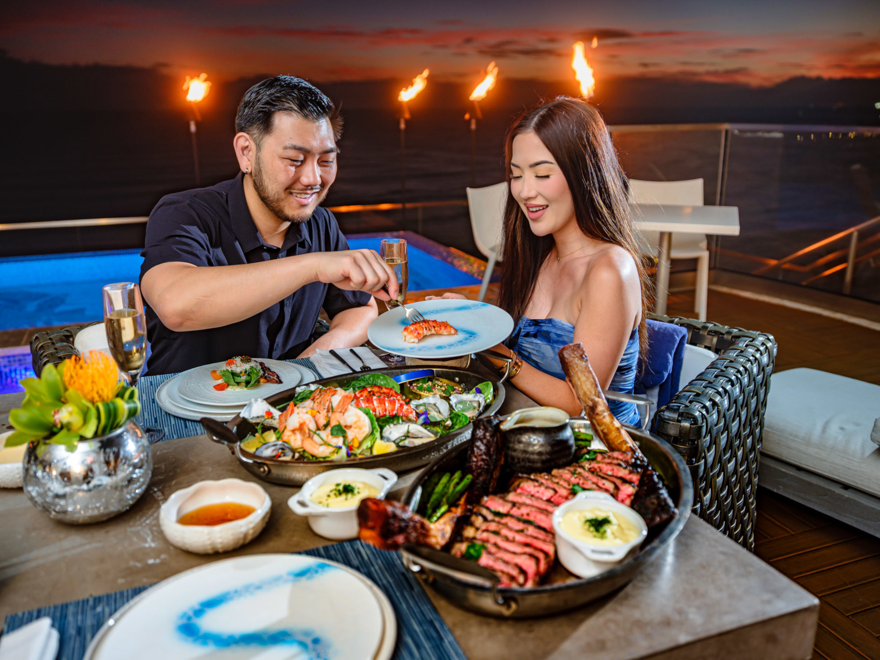 Couple seated on the rooftop at Espacio Waikiki enjoying a shrimp, lobster tail and steak dinner